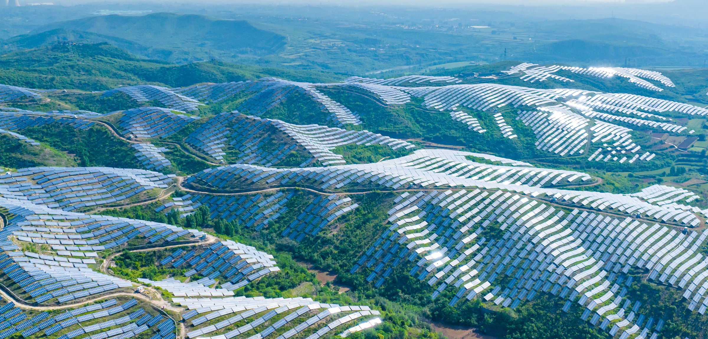 Conceptual aerial rendering of solar arrays across forested hills — concept visual, not the project site, layout or scale